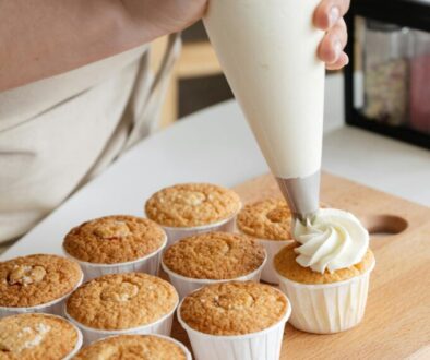 A baker piping frosting onto cupcakes.